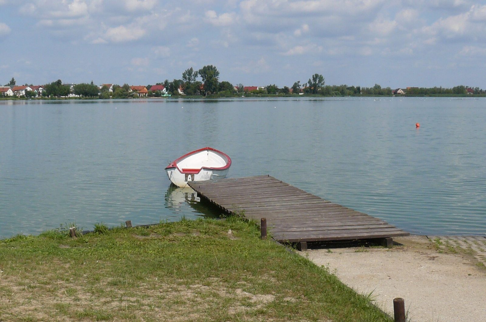 Jezioro Kunickie z brzegu, spokojna tafla wody i linia drzew po drugiej stronie
