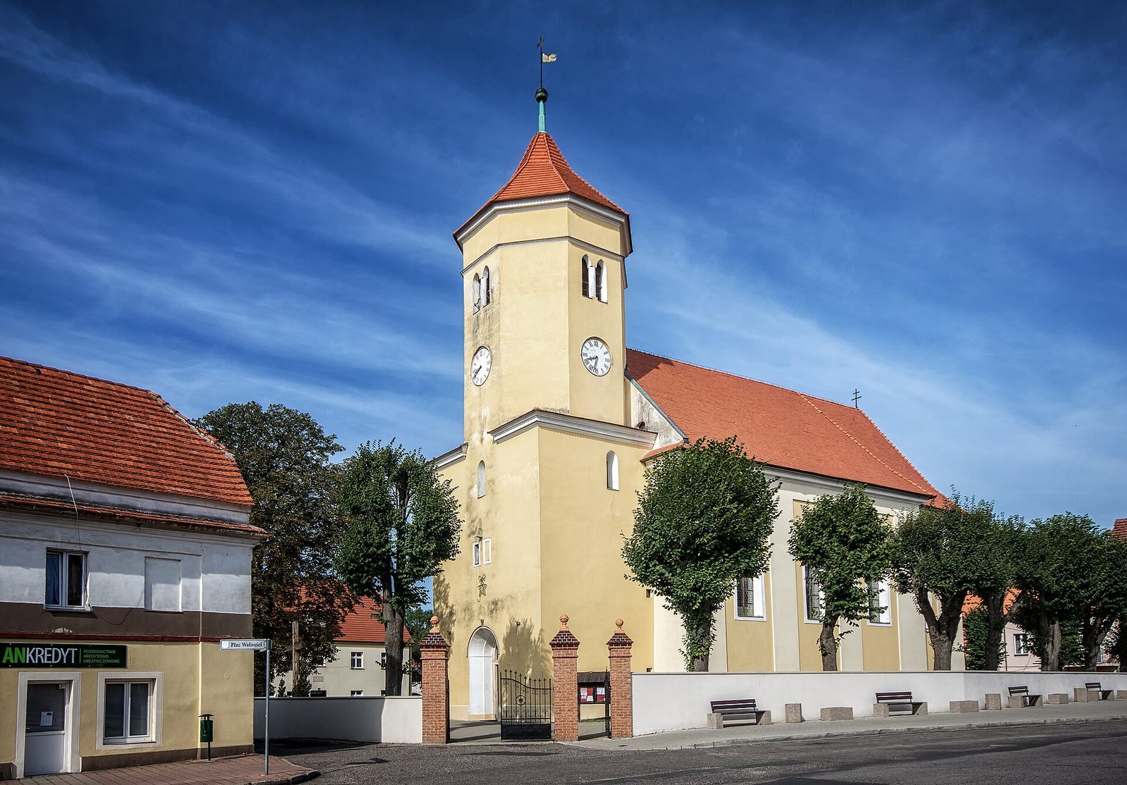 Kościół Wniebowzięcia NMP w Przemkowie, żółte mury, wieża z zegarem i czerwonym dachem
